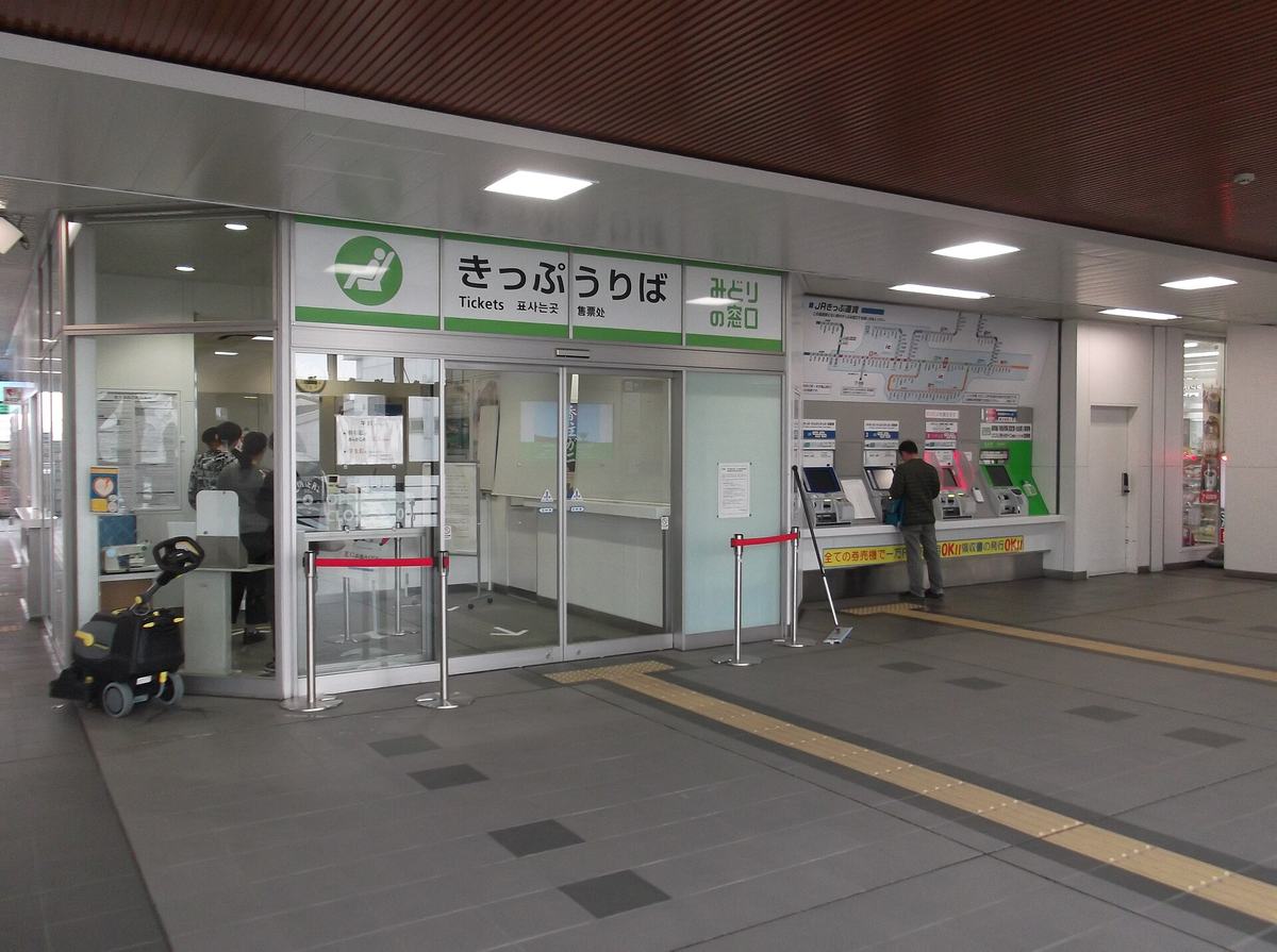駅のきっぷうりば。みどりの窓口の隣に自動券売機が並び、利用客が操作している