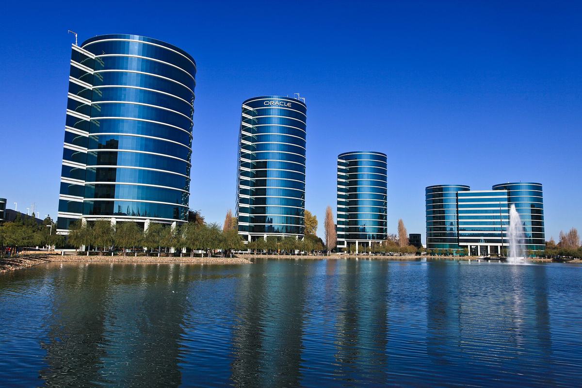 湖越しに見える円柱形のガラス張りビル群。Oracle 旧本社の Redwood Shores キャンパス